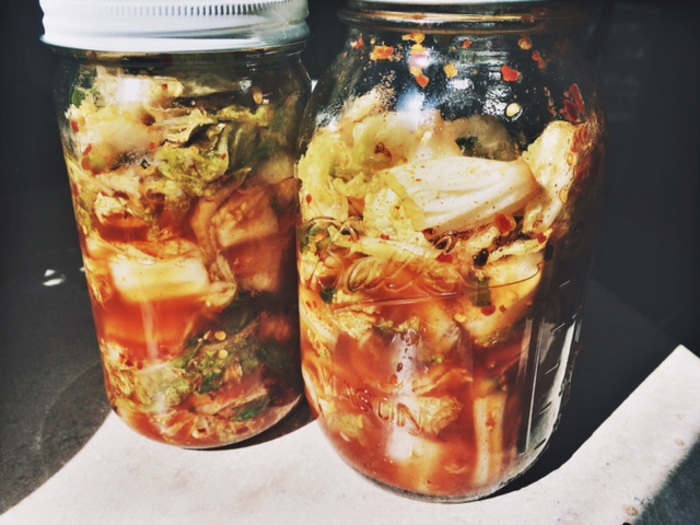 Homemade Vegan Kimchi in two mason jars, lit by sunlight