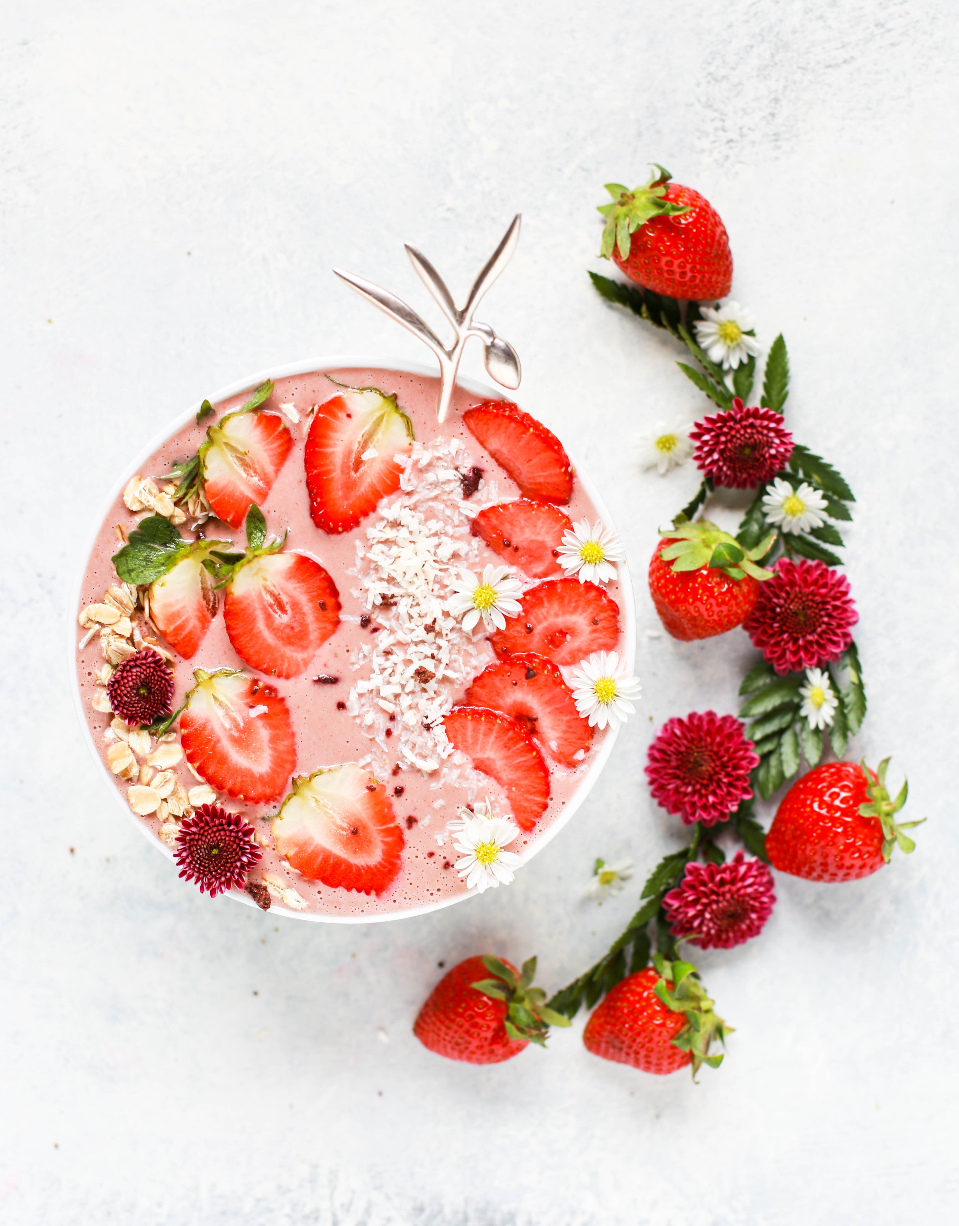 8 Ways to Incorporate Mood Foods into Your Diet: pink smoothie bowl decorated with strawberry slices on a white background.