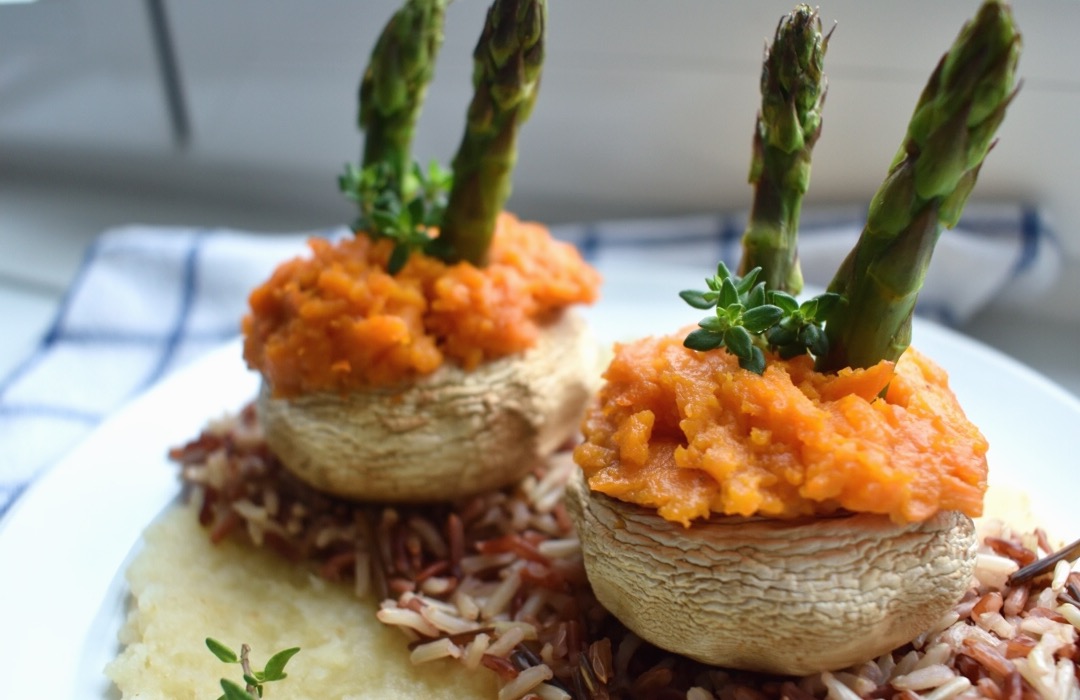 Stuffed Mushrooms with sweet potato mash, topped with asparagus spears, plated and laid on a table