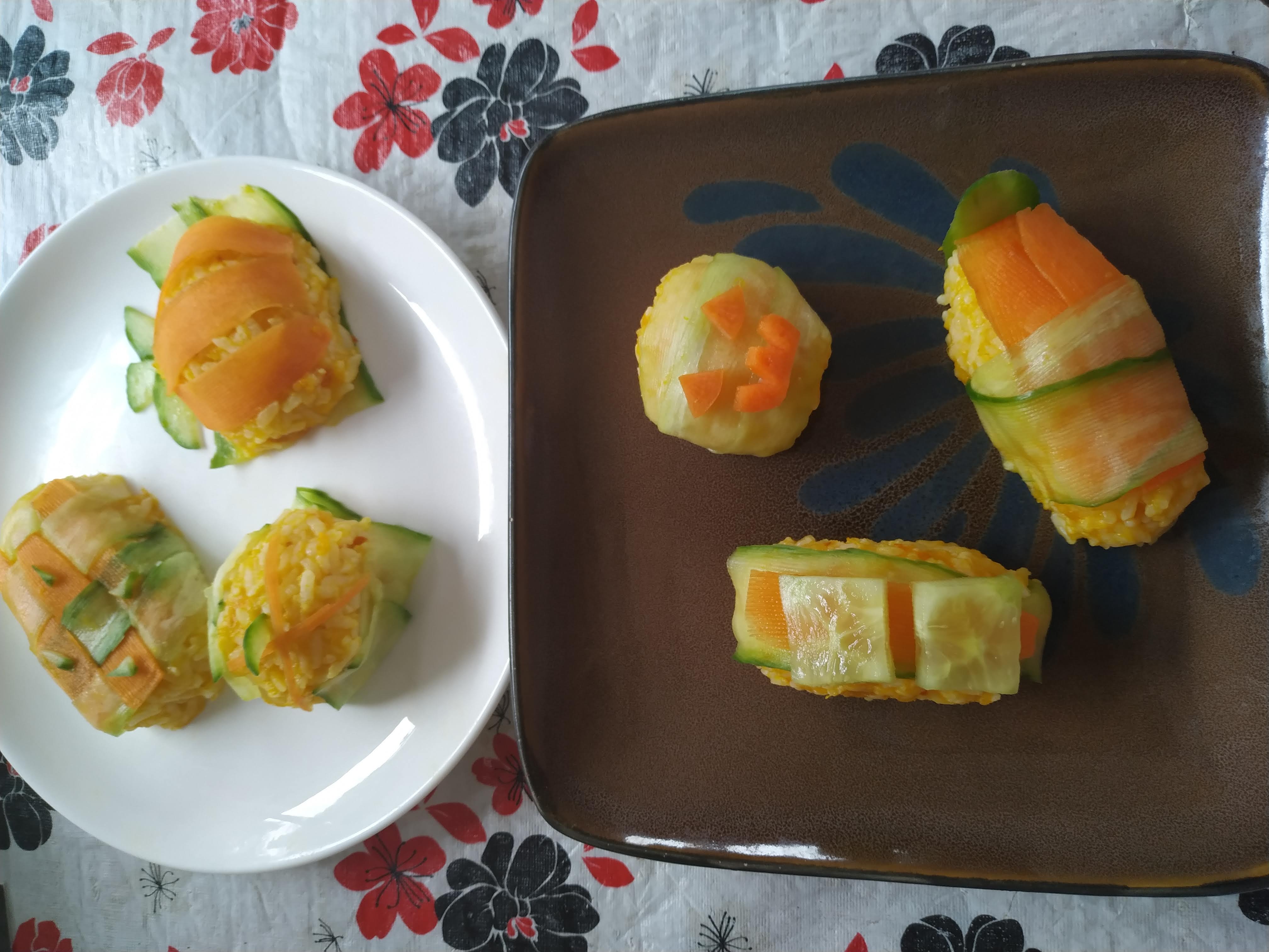 A plate of halloween themed sushi with pumpkin, carrot, rice, and cucumber