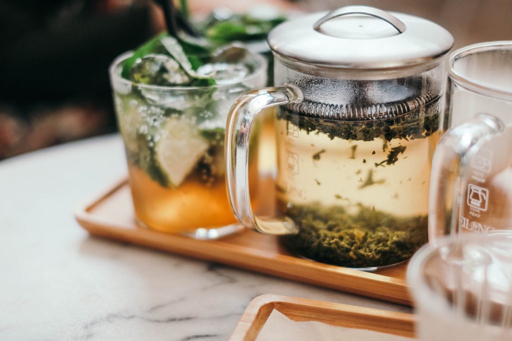 Green tea in a glass tea press on a tray