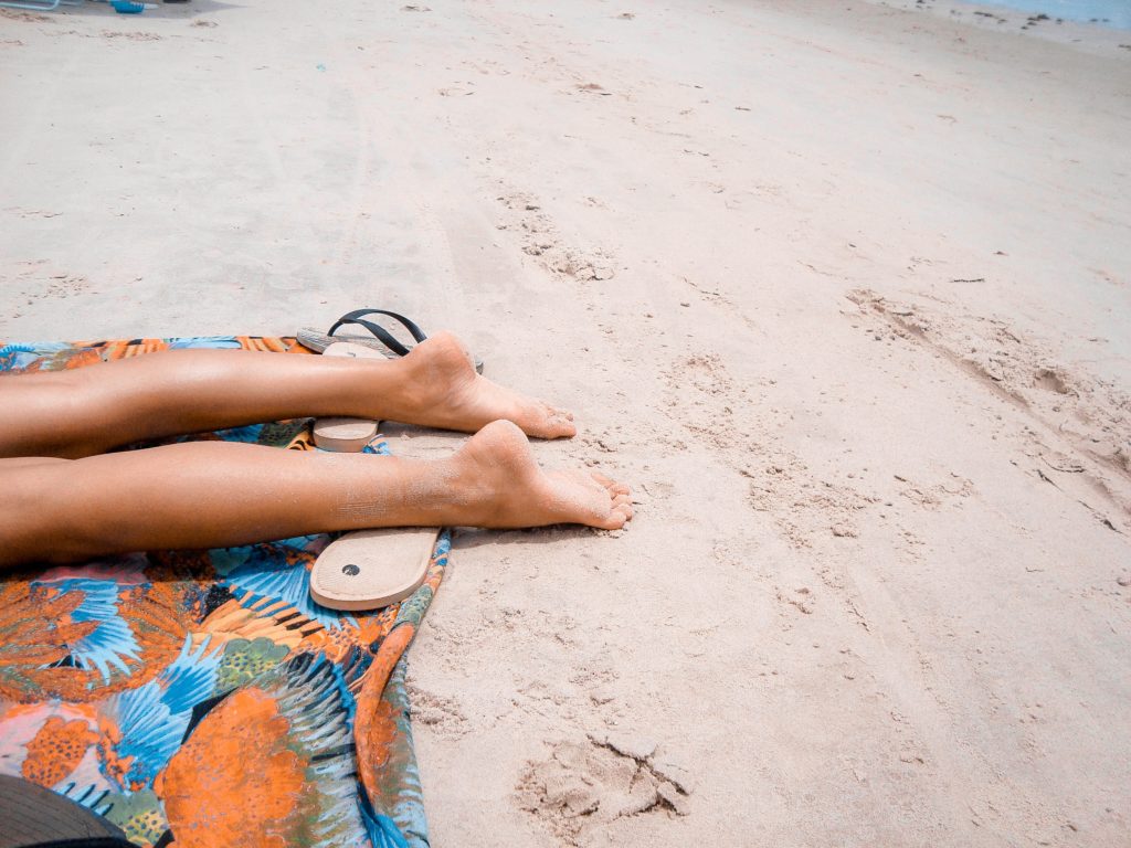 A sunbathers legs on a beach