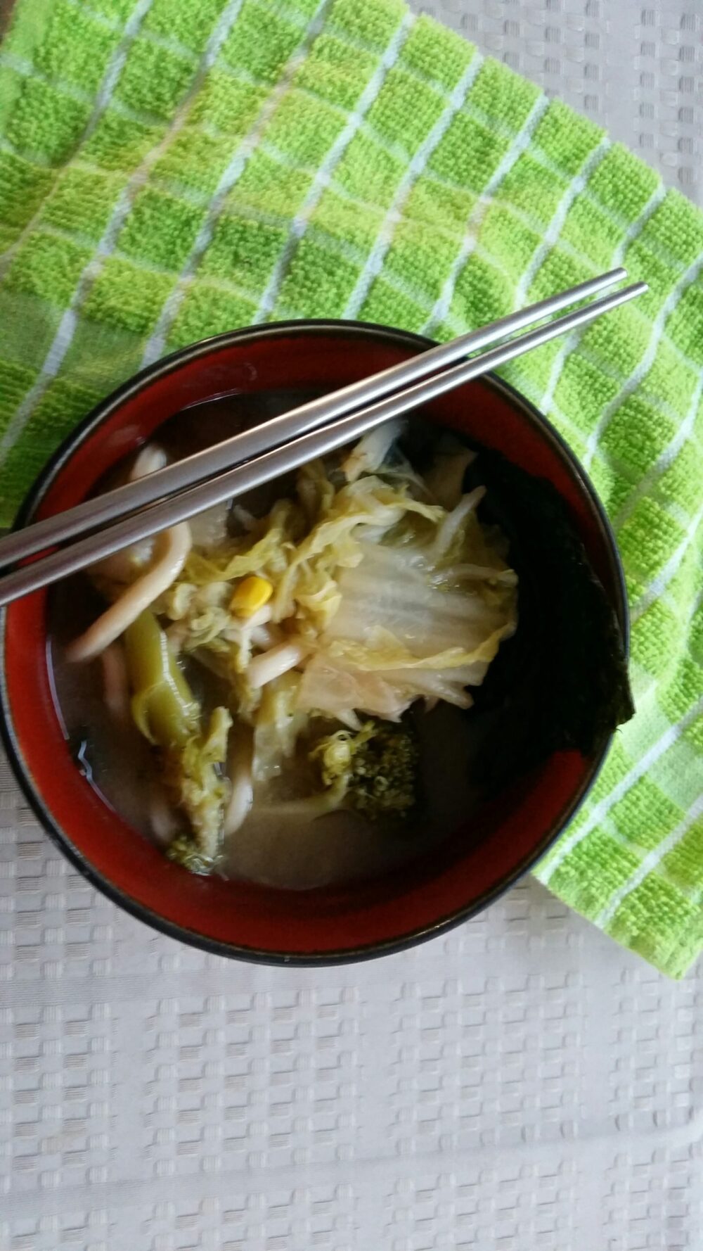 bowl of miso vegetable udon noodle soup with green cloth