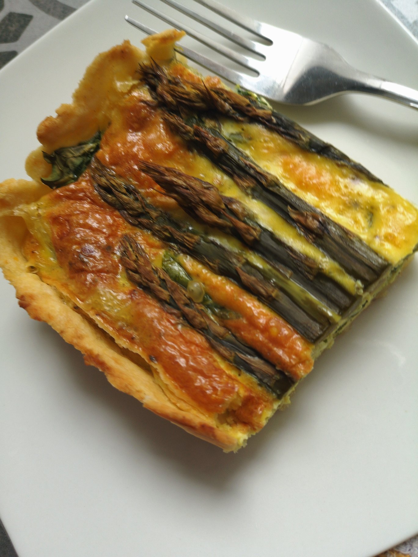 vegan spinach asparagus pie on a white plate with a fork
