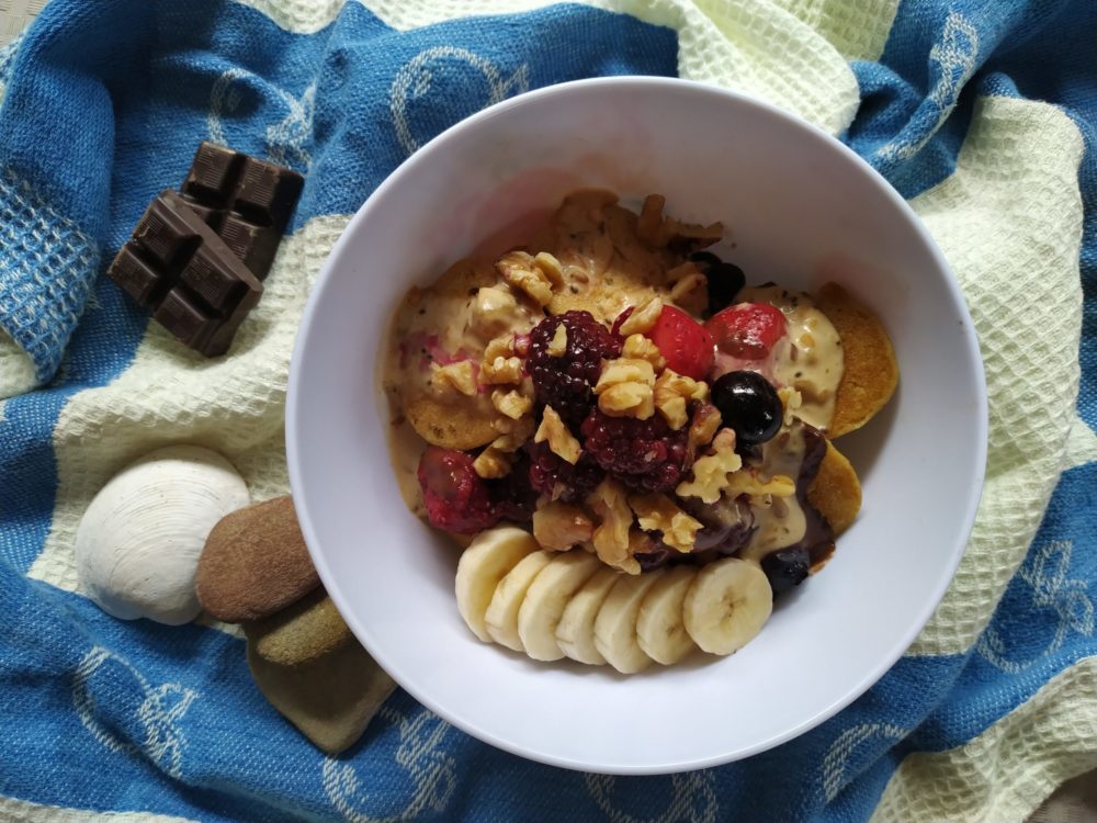 pancake cereal in a bowl with banana, peanut butter, walnuts, and berries