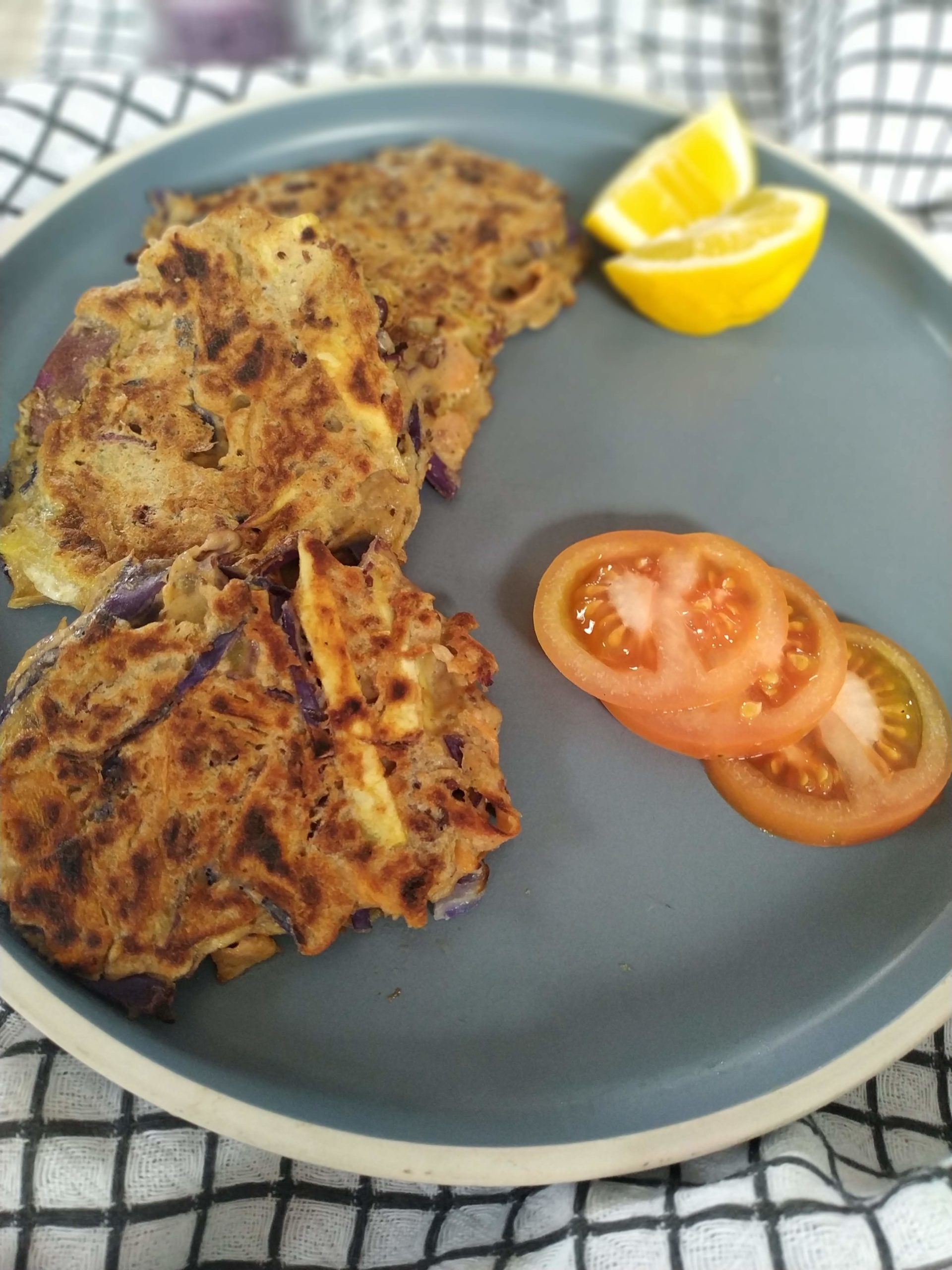 vegetable fritters on a blue plate with slices of tomato and lemon