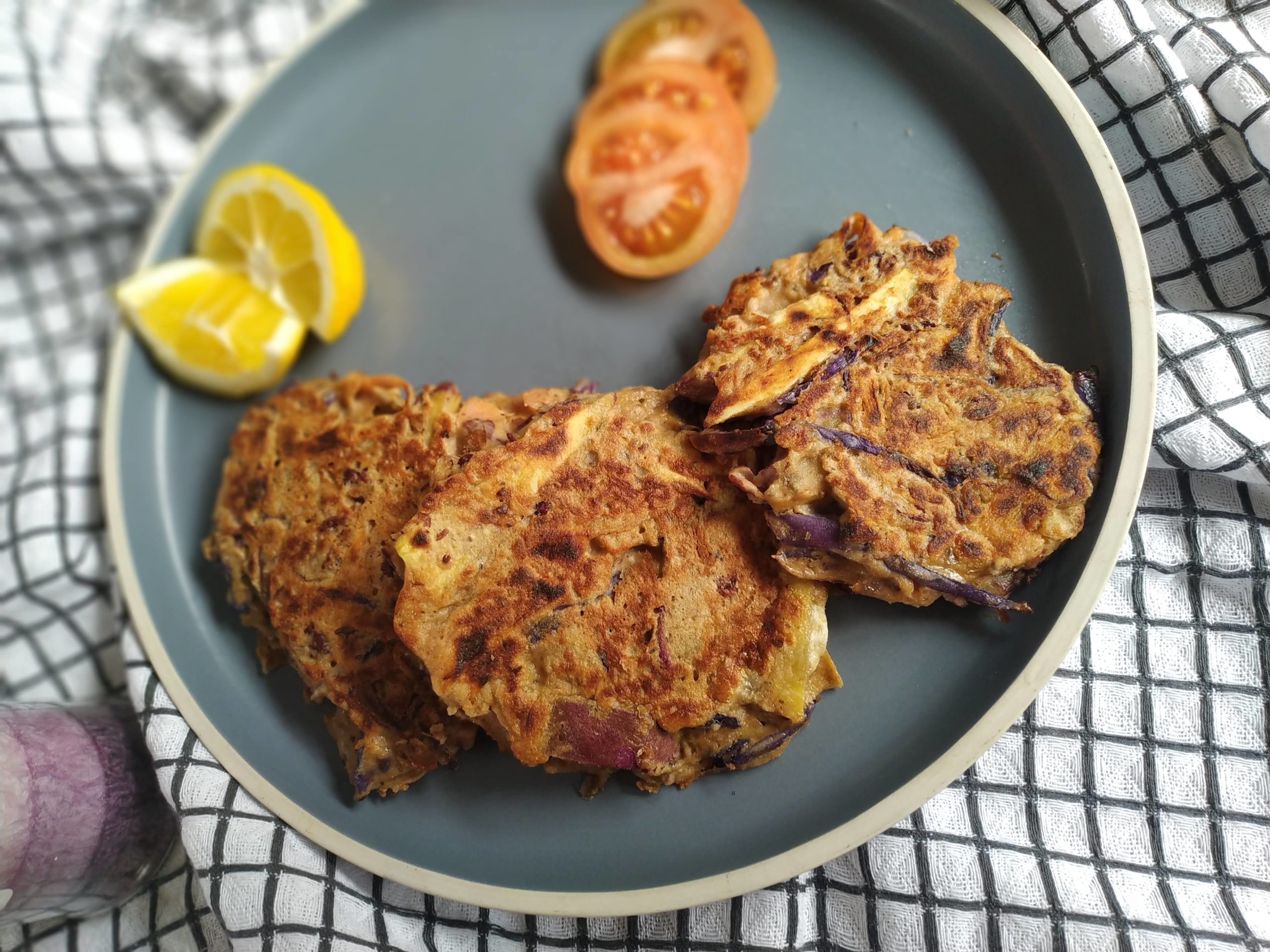 vegetable fritters on a blue plate with slices of tomato and lemon