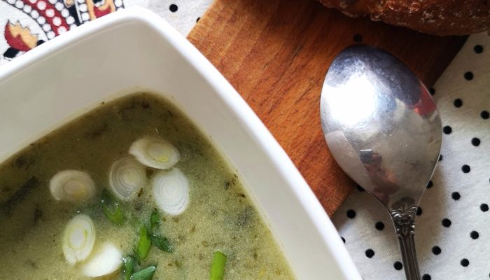 green gazpacho in a white bowl with a spoon