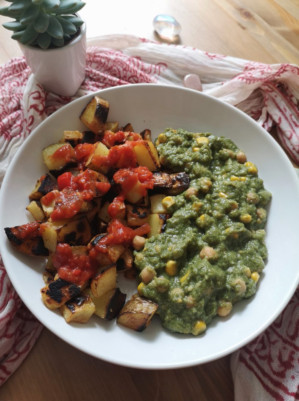 vegan patatas bravas with chickpeas in spinach sauce on a white plate