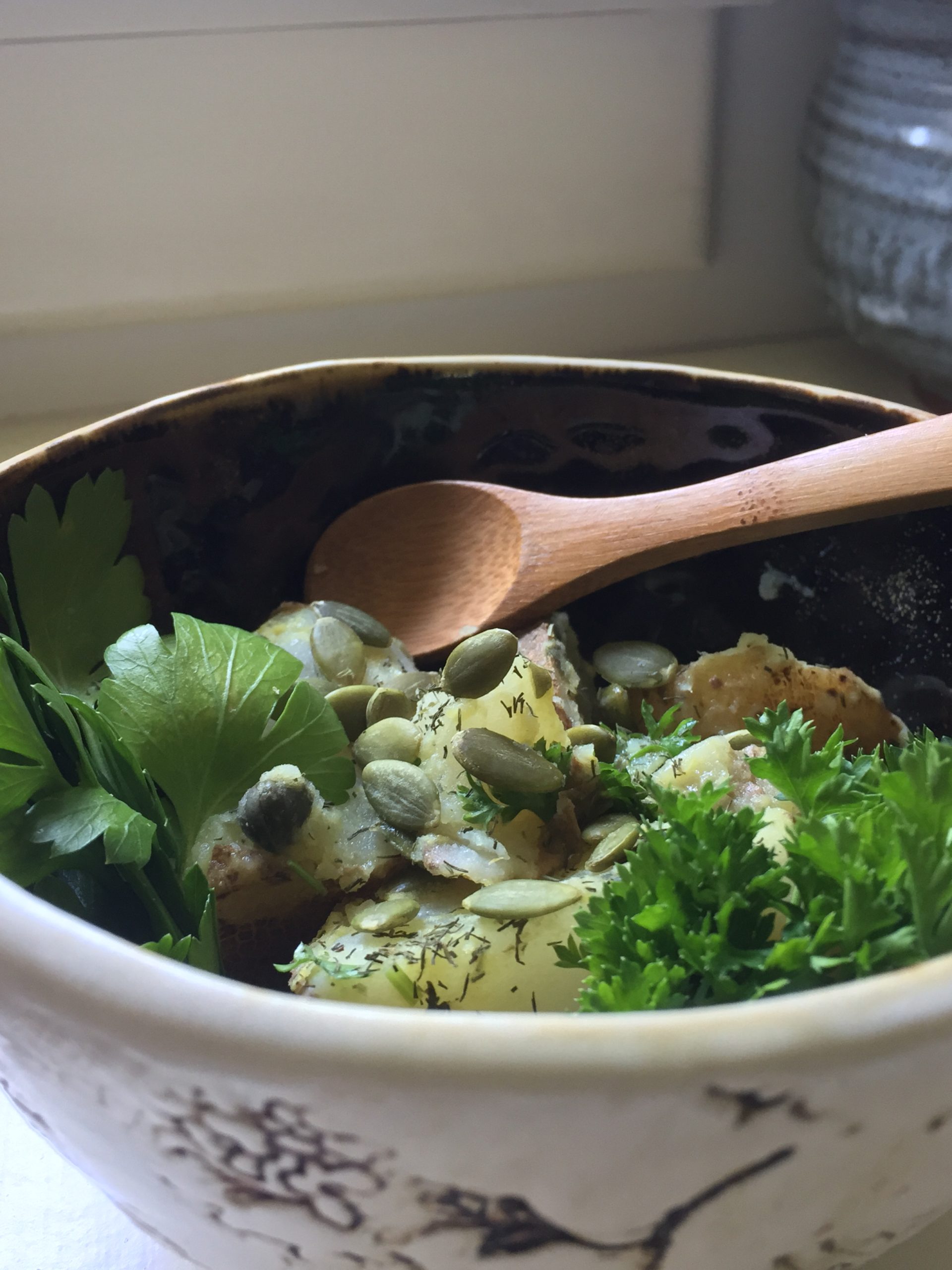 potato salad in a bowl with a wooden spoon