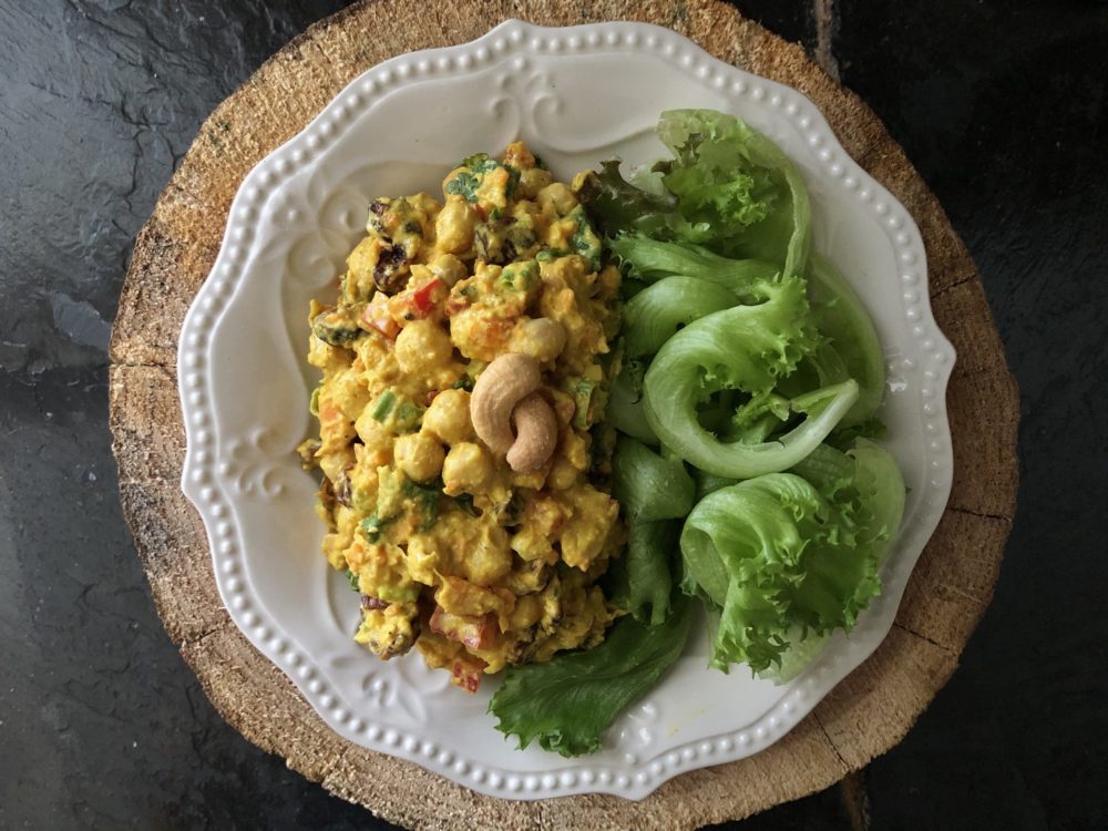 curried chickpea salad on a white plate with a brown and black background