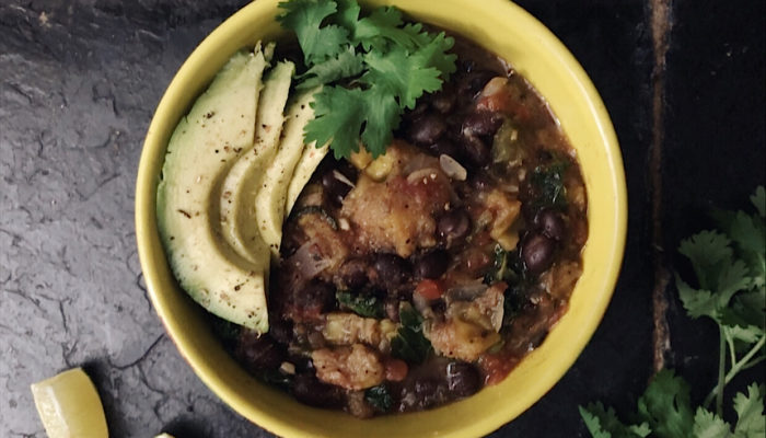 plantain black bean stew in a yellow bowl with black background