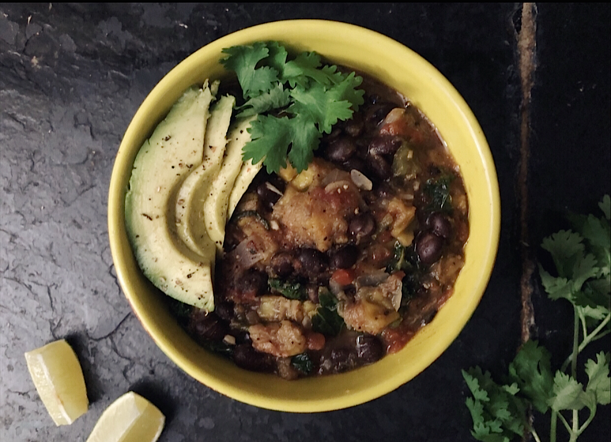 plantain black bean stew in a yellow bowl with black background