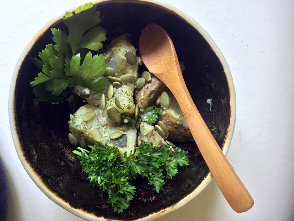 vegan potato salad in a bowl with a wooden spoon