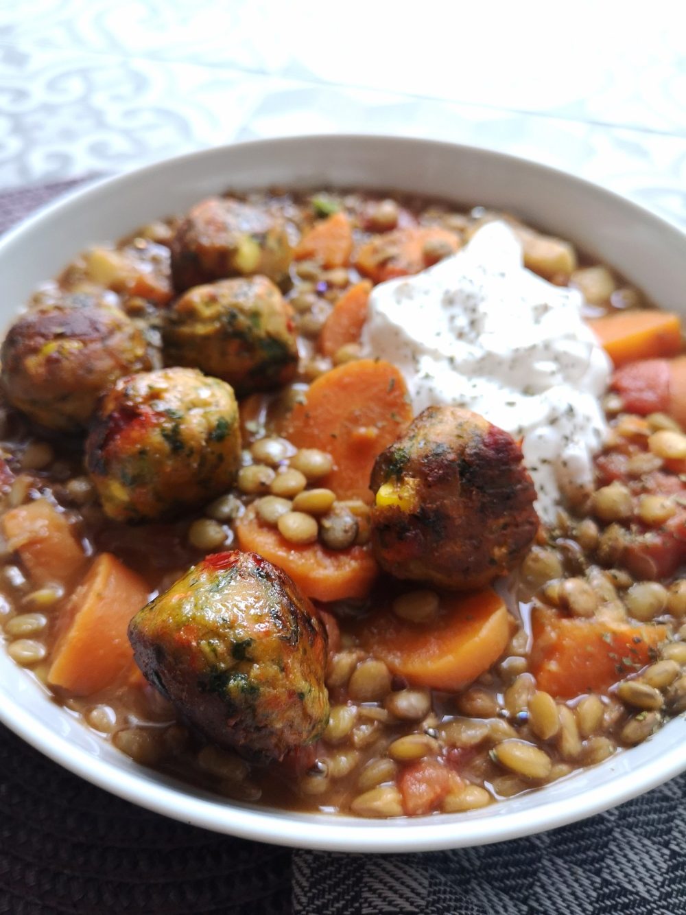 vegan lentil ragout with tomato and veggie balls in a white bowl