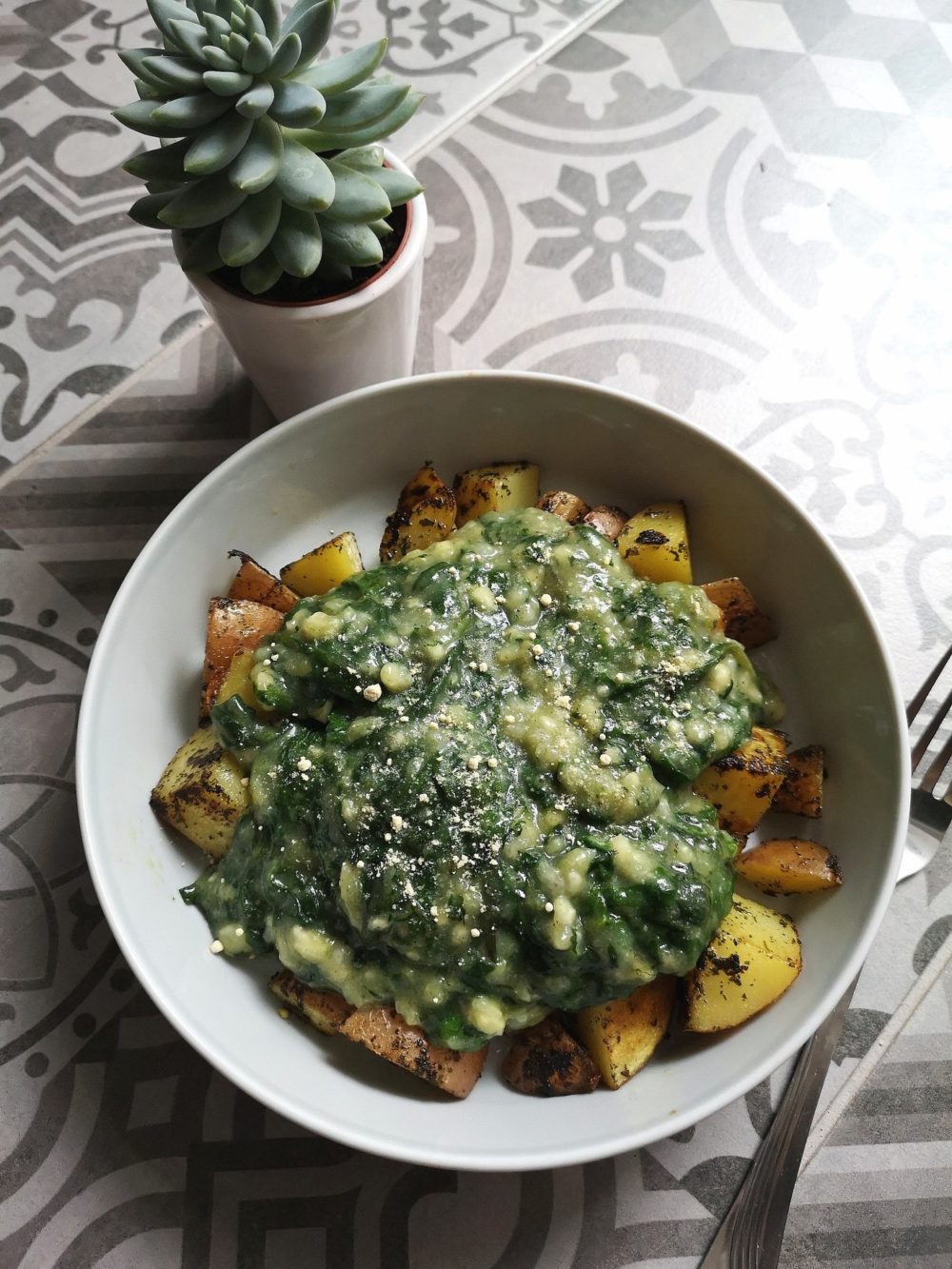 Vegan Creamed Spinach in a white bowl next to a succulent