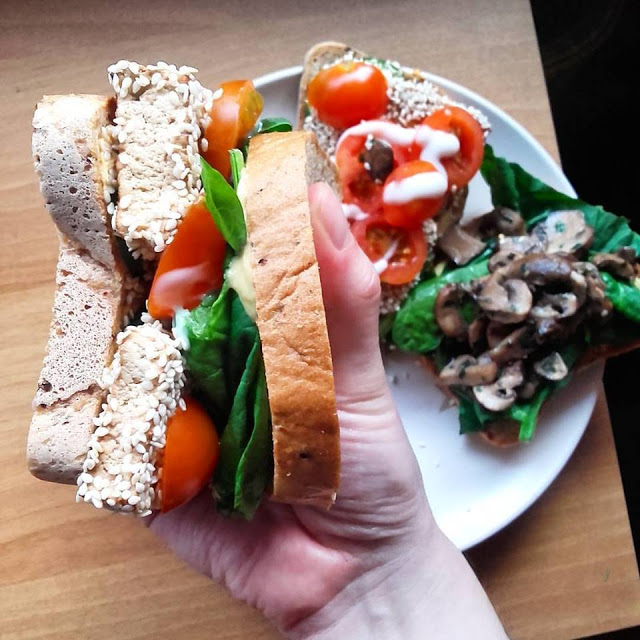 a hand holding a vegan grilled sesame tofu sandwich