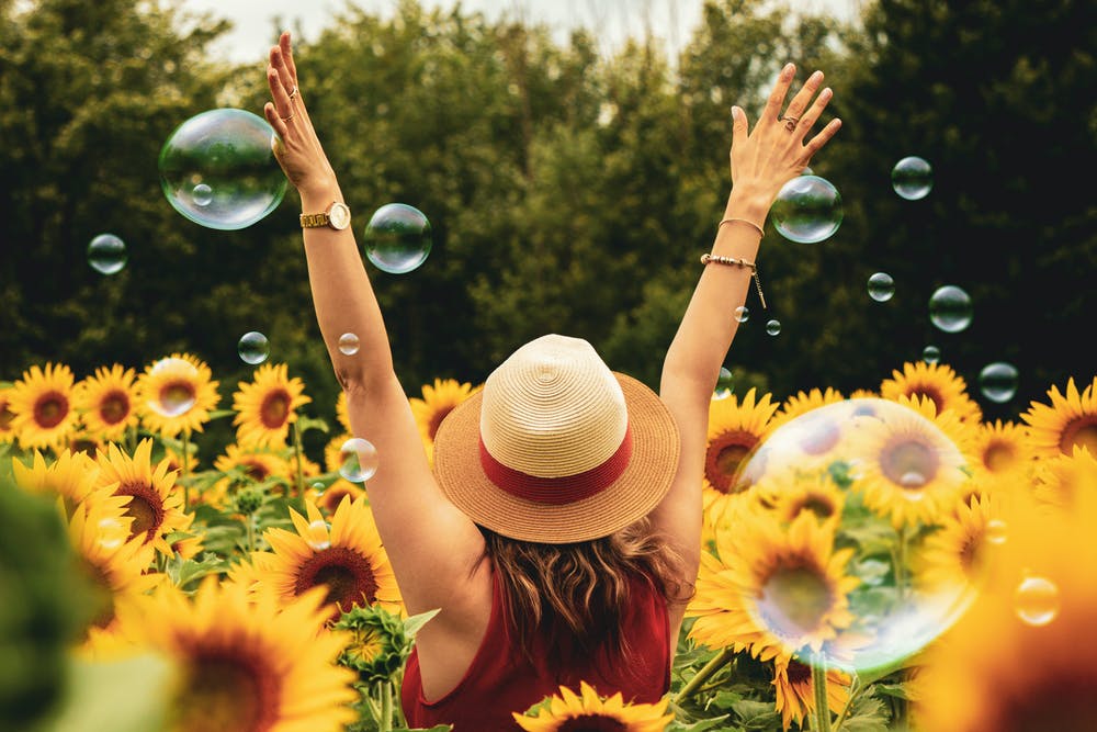 woman in field with sunflowers and bubbles