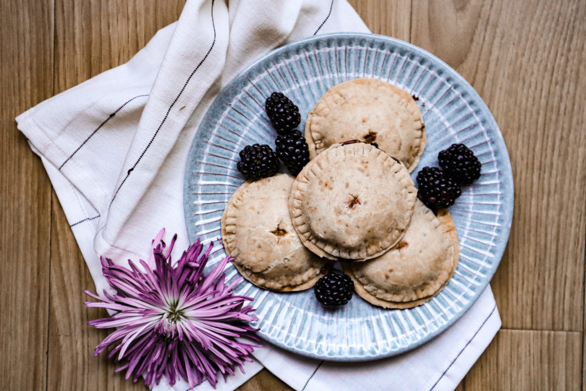 vegan blackberry apple hand pies on a blue plate with a purple flower