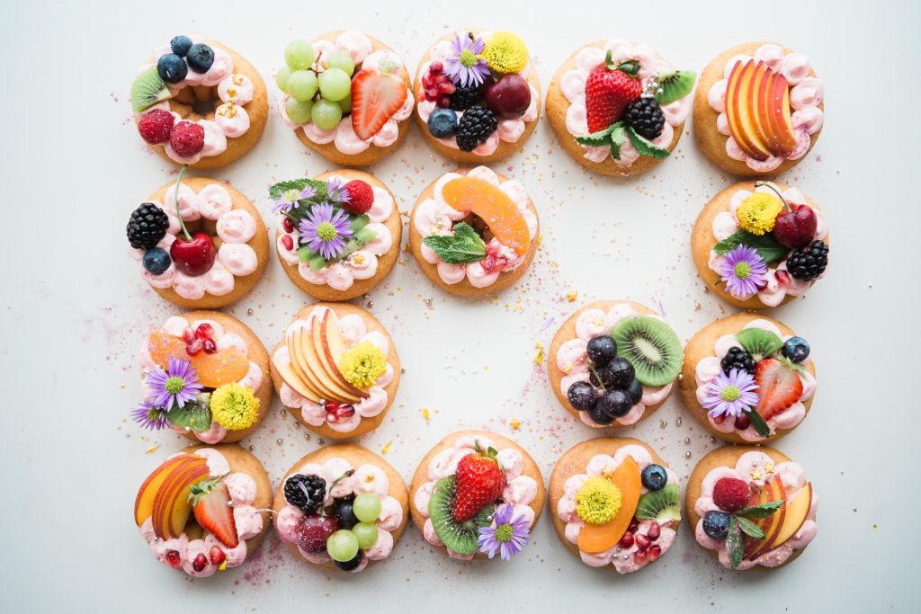 An array of donuts topped with various fruits