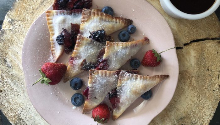 mixed berry turnovers on a plate with brown background