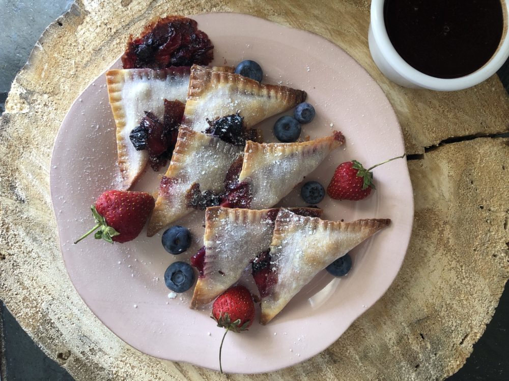 mixed berry turnovers on a plate with brown background