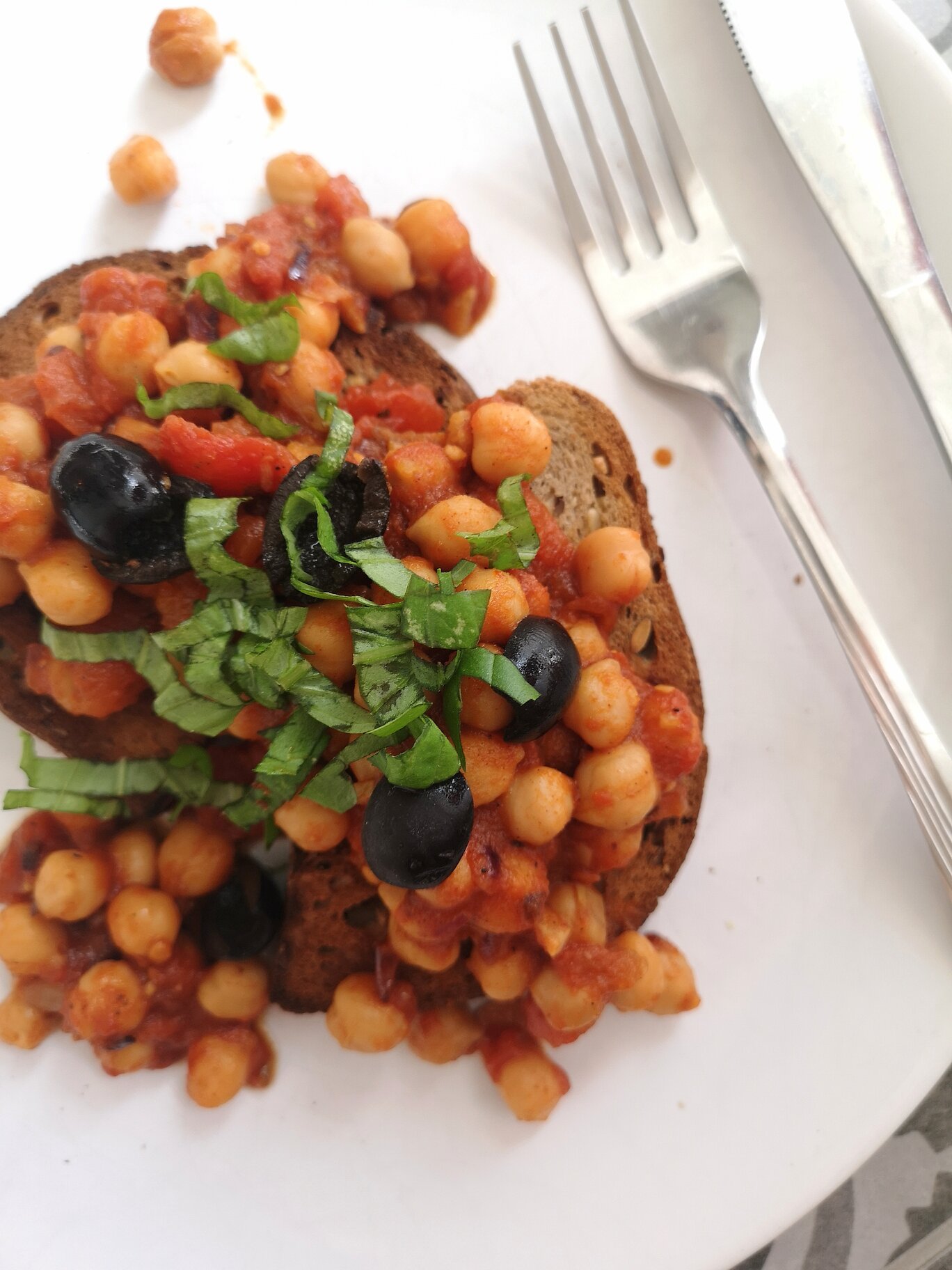 greek chickpeas on toast on a white plate with a fork