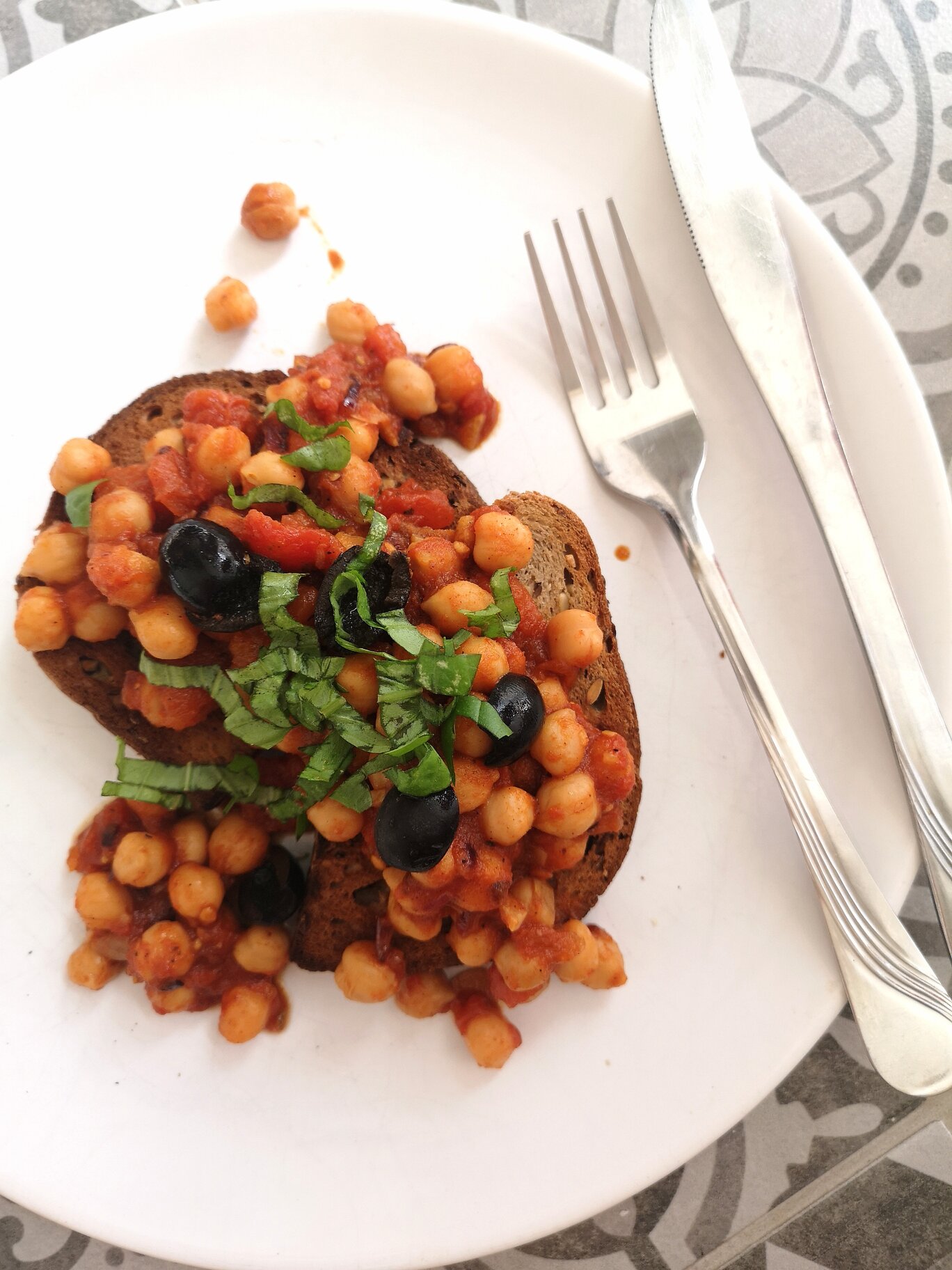 greek chickpeas on toast on a white plate with a fork