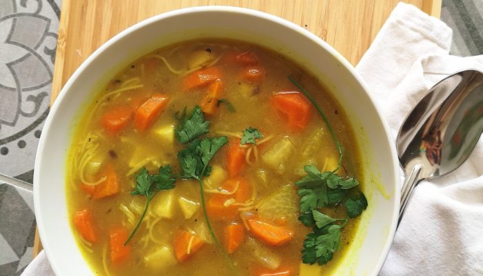 heirloom vegan hungarian thread noodle soup in a white bowl with a spoon