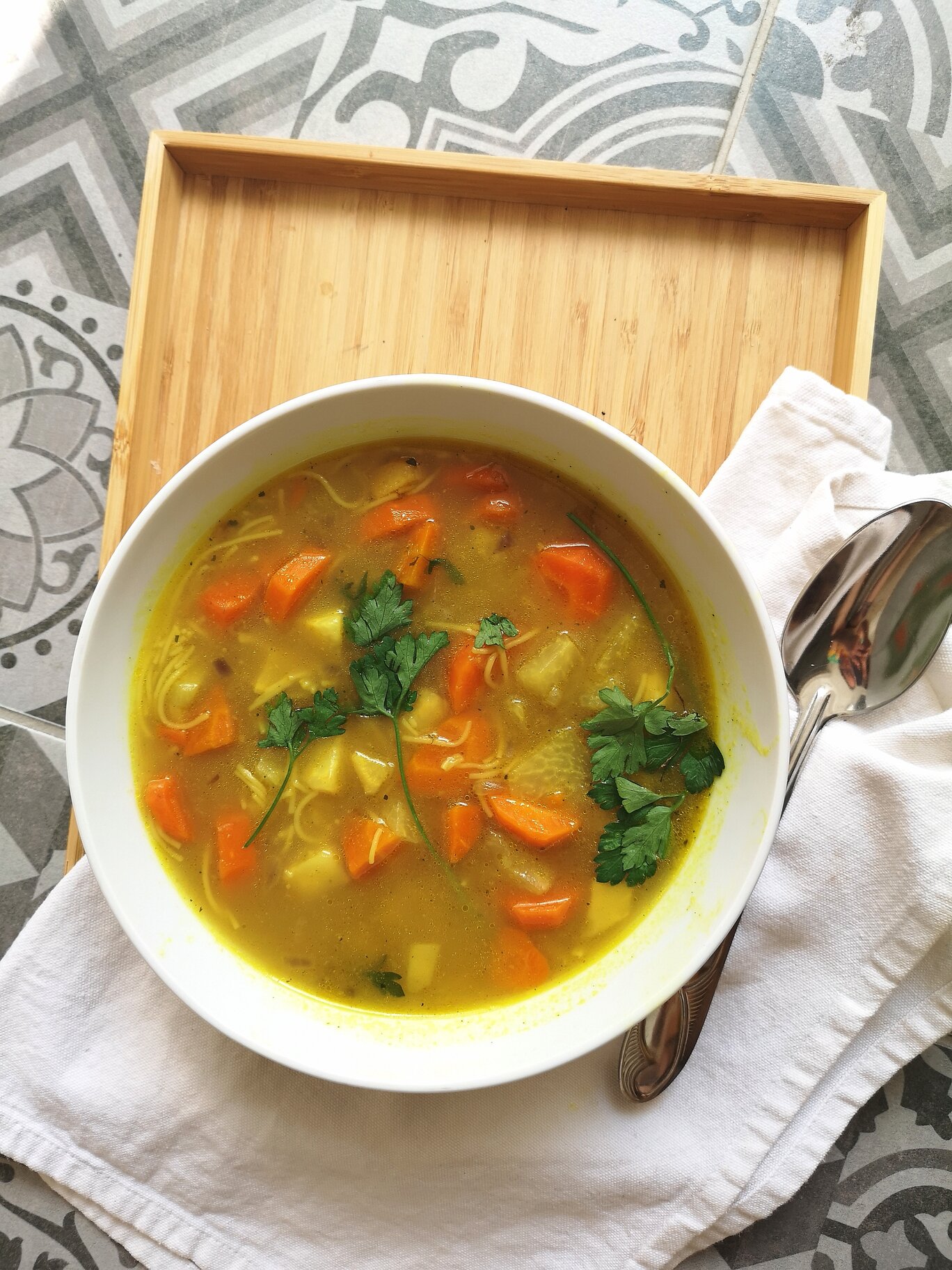 heirloom vegan hungarian thread noodle soup in a white bowl with a spoon