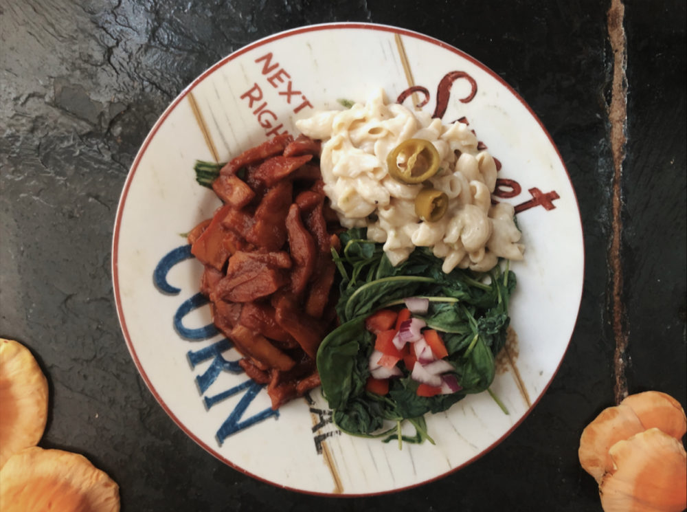 vegan barbecue chicken of the woods on a plate with black background