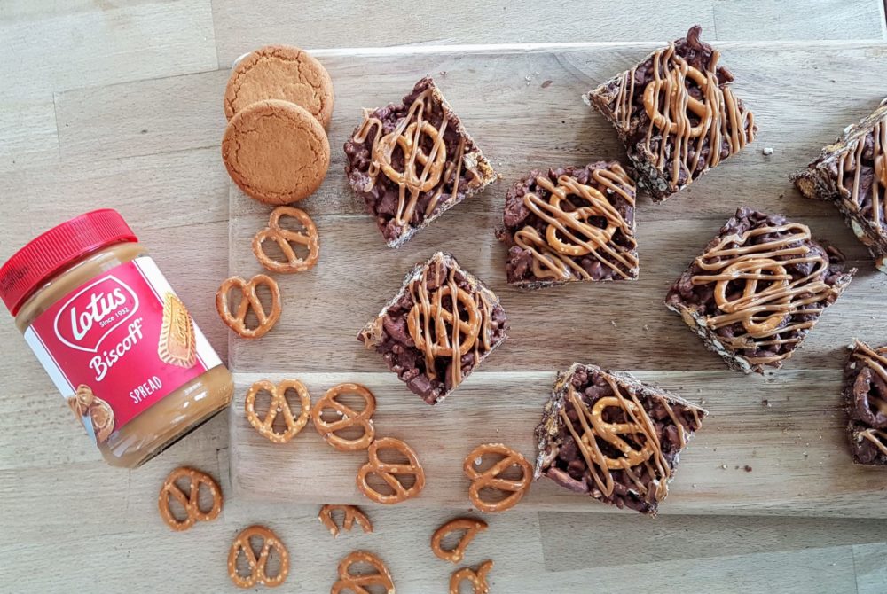 vegan biscoff rocky road bars on a cutting board next to pretzels and biscoff jar