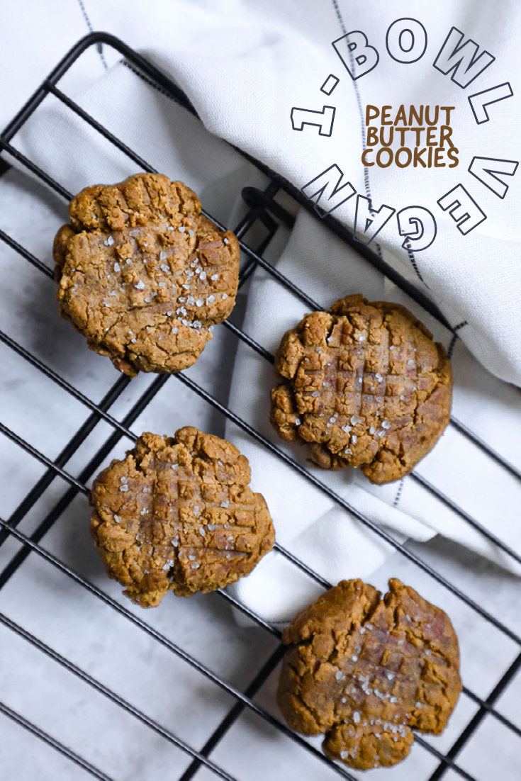 vegan peanut butter cookies on a wire cooling rack. a white tea towel is visible above with overlayed caption