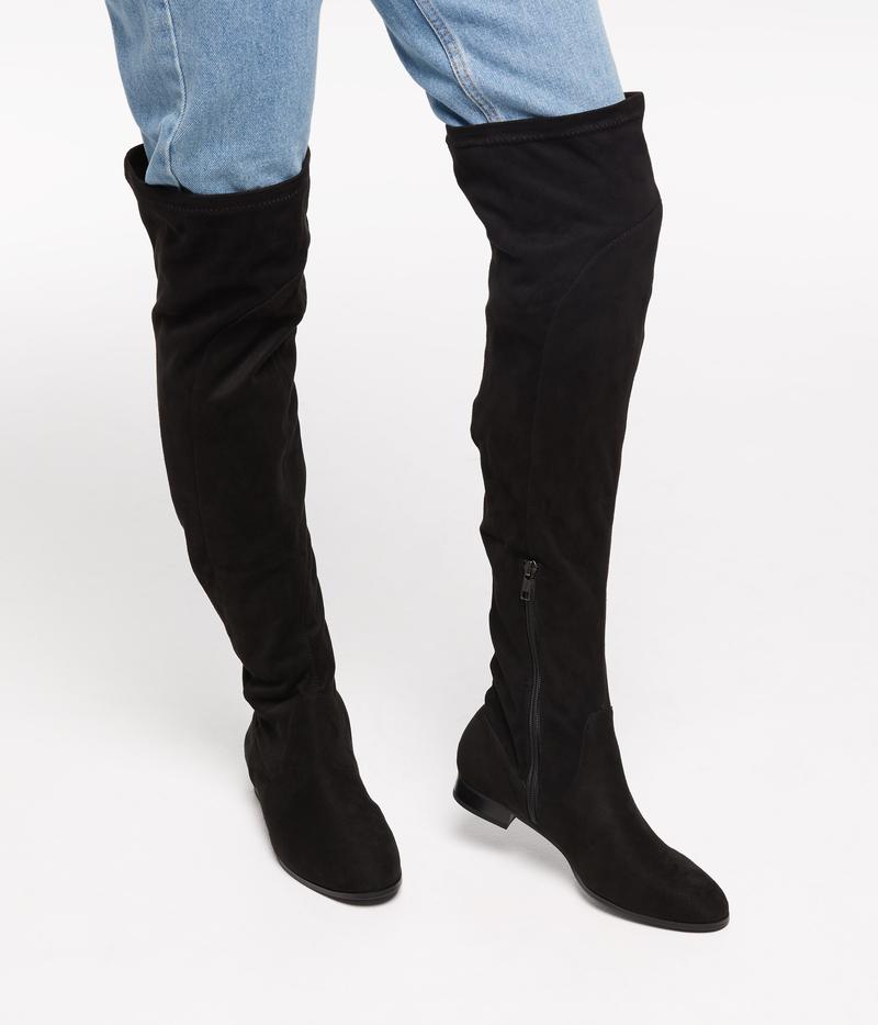 a person wearing tall black boots with a white background