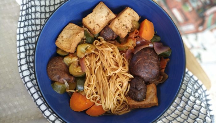 taiwanese noodle soup with tofu and vegetables in a blue bowl