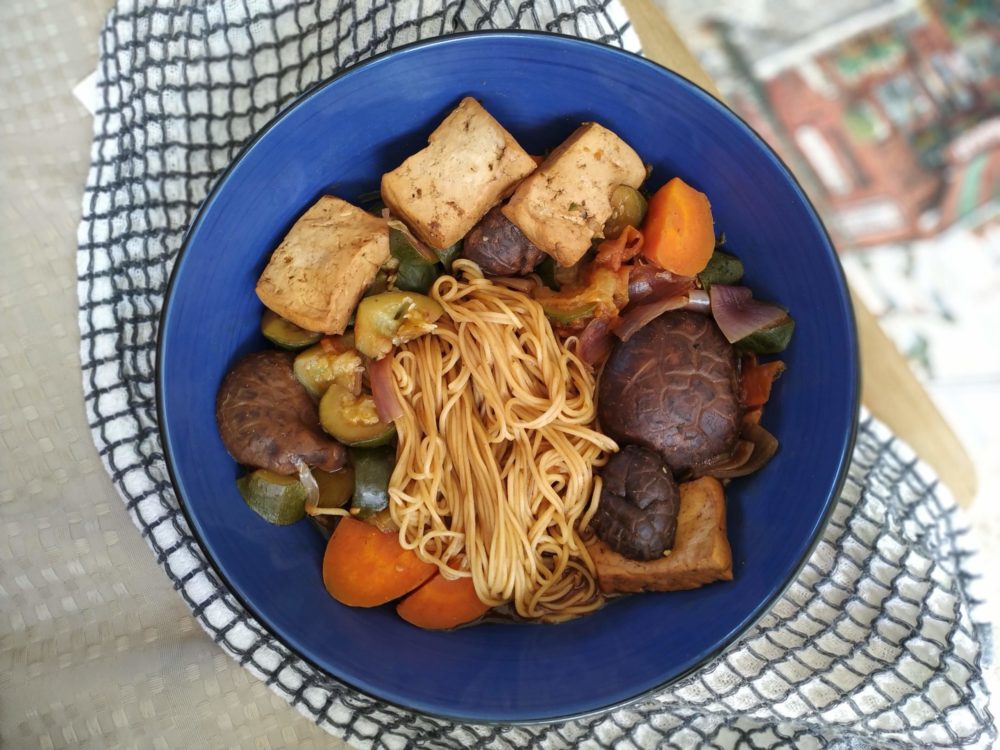 taiwanese noodle soup with tofu and vegetables in a blue bowl