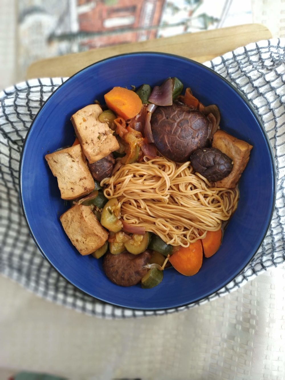 taiwanese noodle soup with tofu and vegetables in a blue bowl