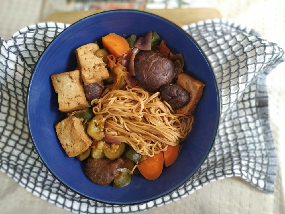 taiwanese noodle soup with tofu and vegetables in a blue bowl