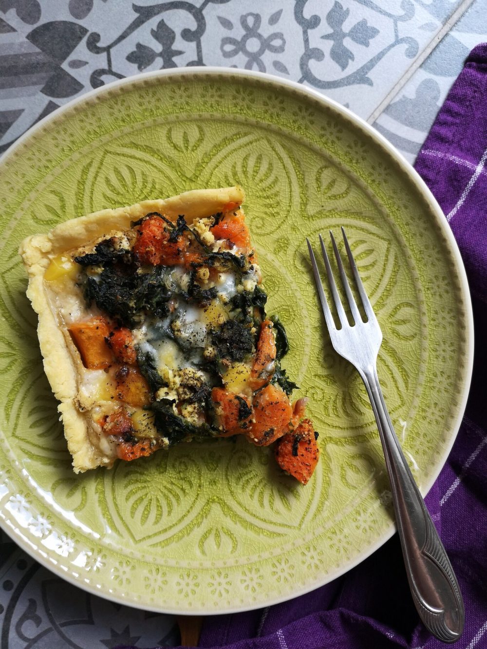 butternut squash quiche with spinach and feta on a green plate with a fork