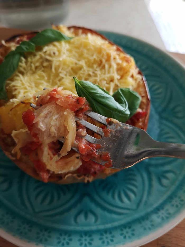 spaghetti squash on a blue plate with silverware