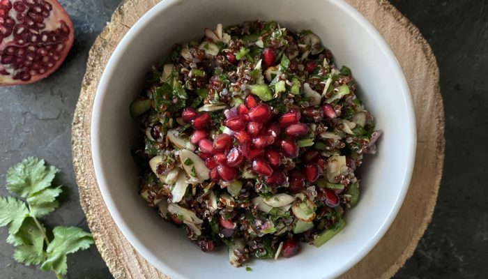 pomegranate almond tabouleh in a white dish against a brown and black background