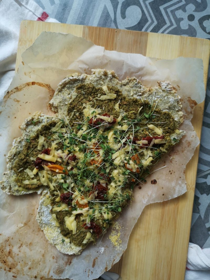 cauliflower pizza with microgreens on a wooden cutting board