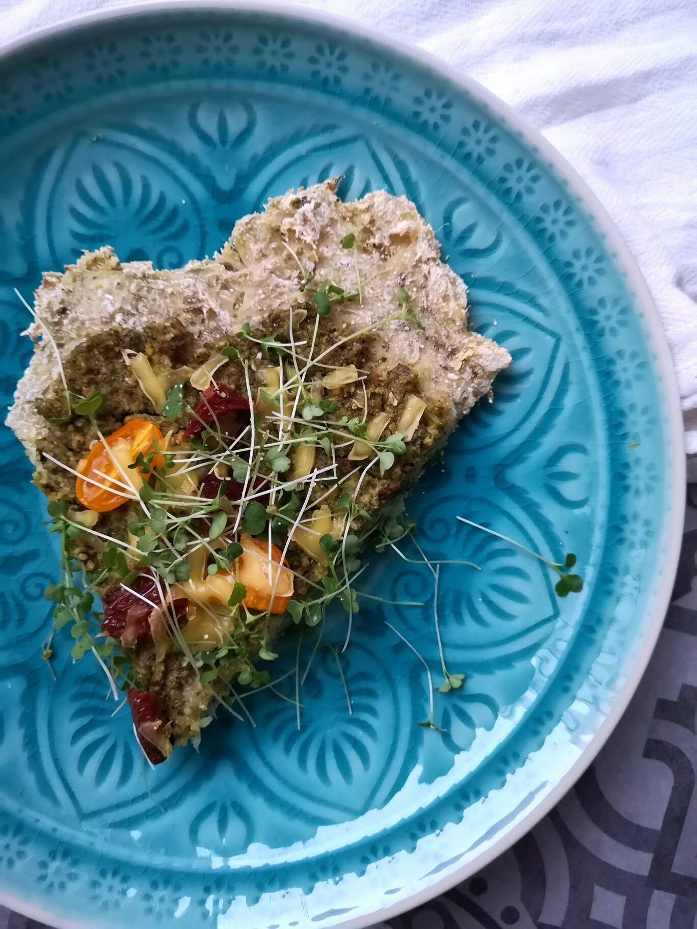 cauliflower pizza with microgreens pesto on a blue plate