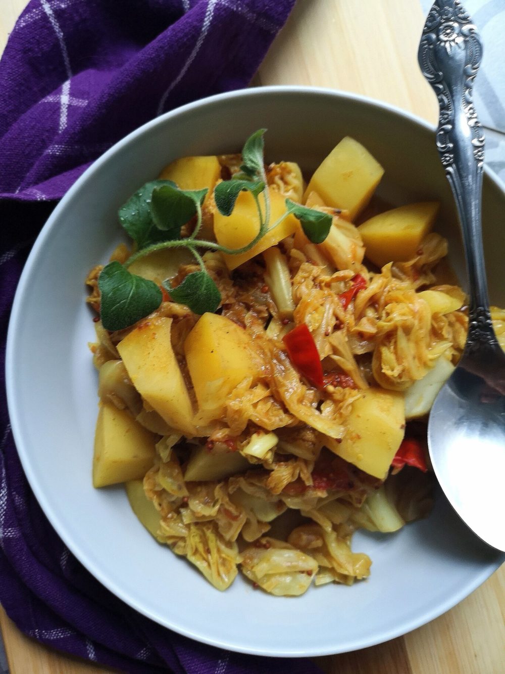 vegan cabbage potato sabji in a bowl with a spoon