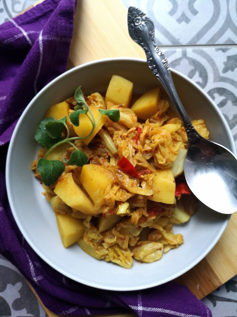 vegan cabbage potato sabji in a bowl with a spoon