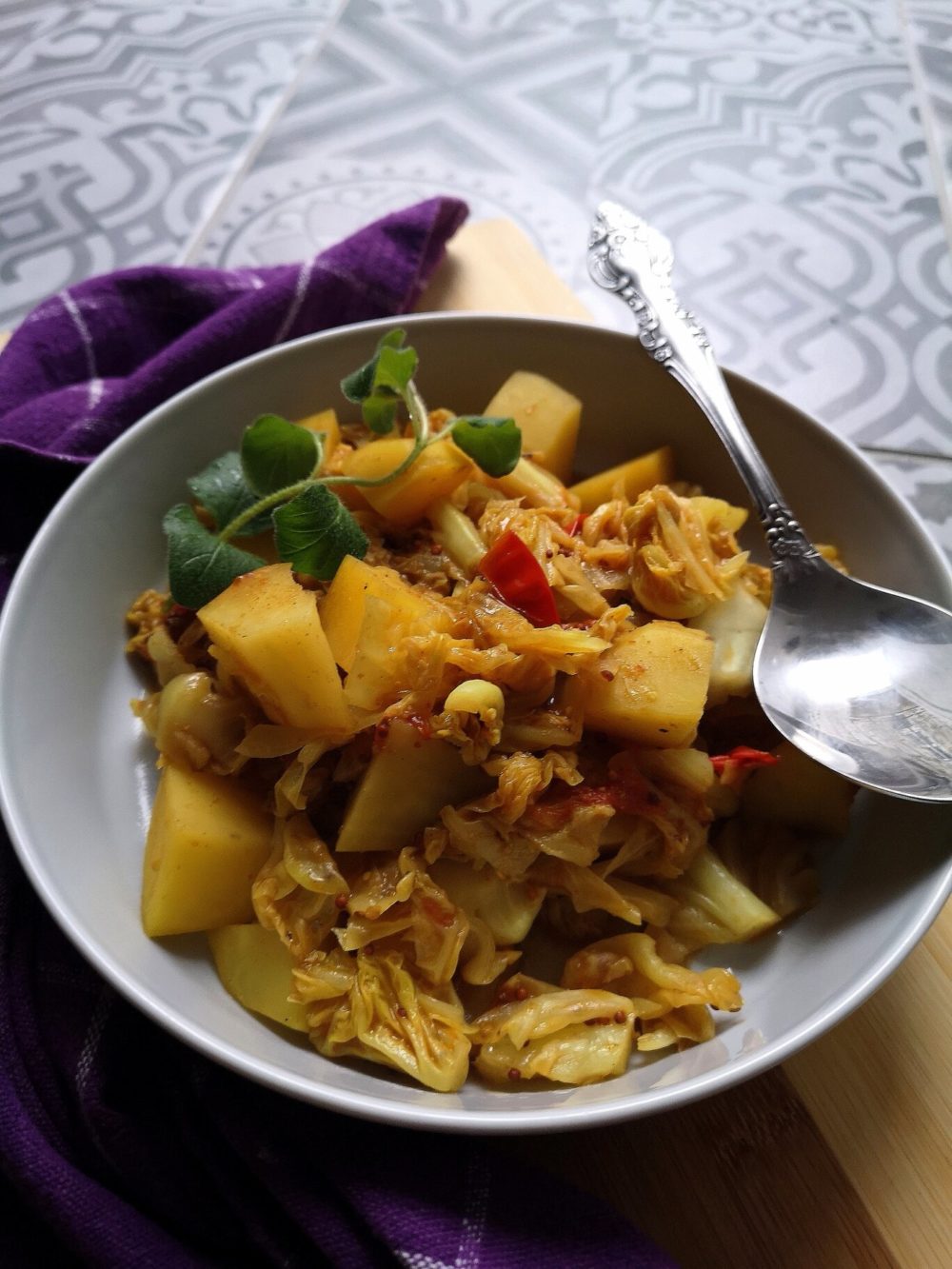 vegan cabbage potato sabji in a bowl with a spoon