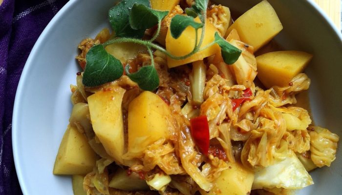 vegan cabbage potato sabji in a bowl with a spoon