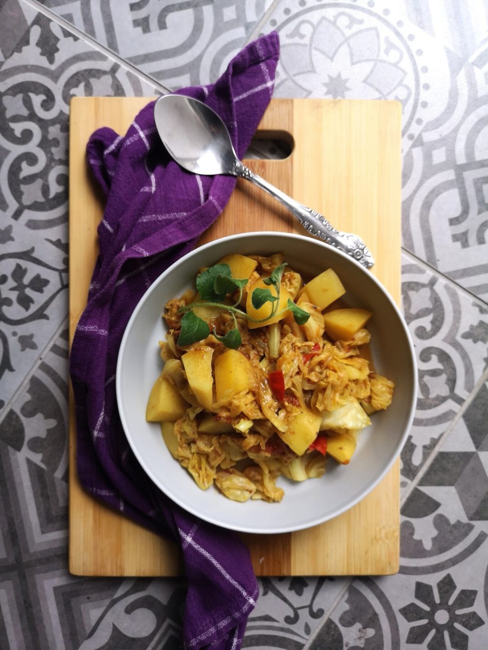 vegan cabbage potato sabji in a bowl with a spoon