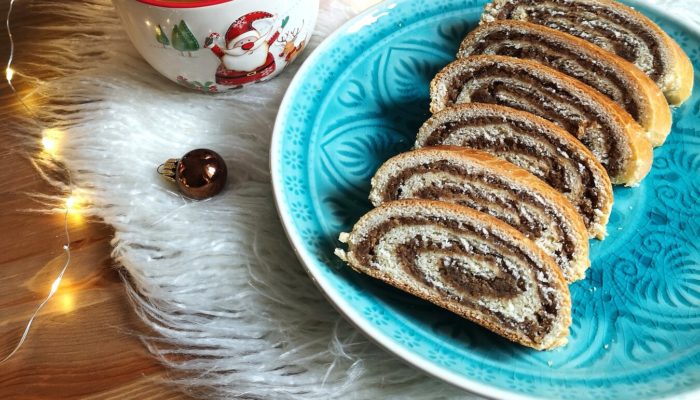 vegan bejgli; hungarian walnut roll on a blue plate with a cup of tea