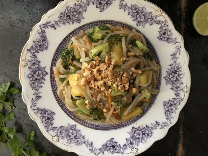 vegan pineapple pad thai on a floral plate with a dark background